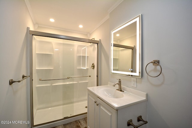 bathroom featuring hardwood / wood-style floors, vanity, a shower with door, and ornamental molding