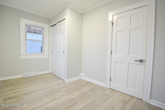 unfurnished bedroom with light hardwood / wood-style floors, ornamental molding, and a closet