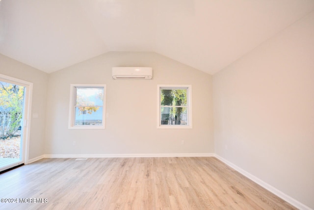 spare room featuring vaulted ceiling, light hardwood / wood-style flooring, and a wall unit AC