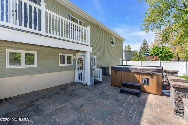 view of patio with a balcony and a hot tub