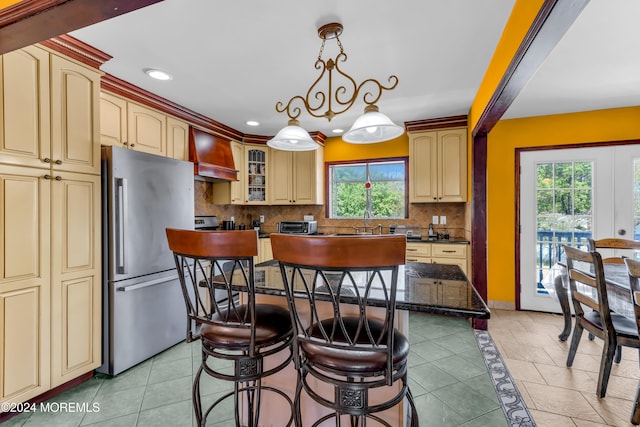 kitchen featuring premium range hood, stainless steel refrigerator, a wealth of natural light, and a center island