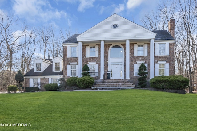 neoclassical home featuring a front lawn