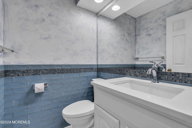 bathroom with vanity, toilet, and tile walls