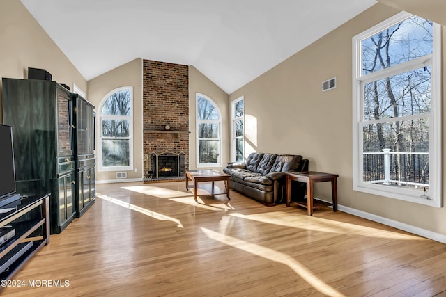 living room with high vaulted ceiling, light hardwood / wood-style floors, a fireplace, and a wealth of natural light