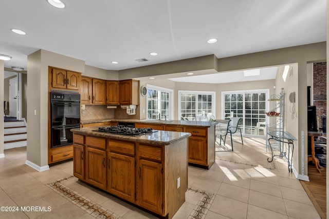 kitchen featuring tasteful backsplash, plenty of natural light, a kitchen island, and black appliances