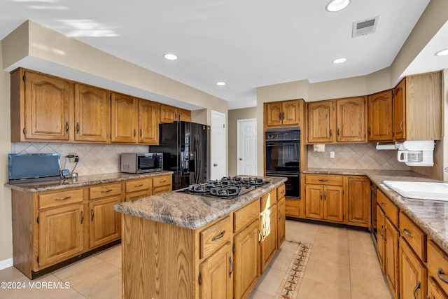 kitchen with decorative backsplash, a center island, black appliances, and sink