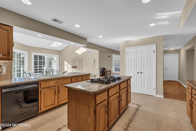 kitchen with stainless steel gas stovetop, dishwasher, light tile patterned flooring, sink, and a kitchen island