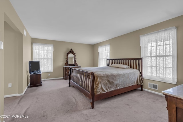 bedroom with light colored carpet and multiple windows