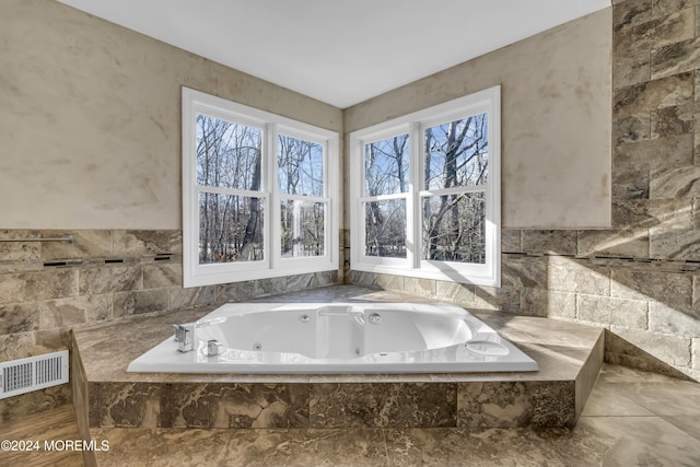 bathroom with tiled bath and a healthy amount of sunlight