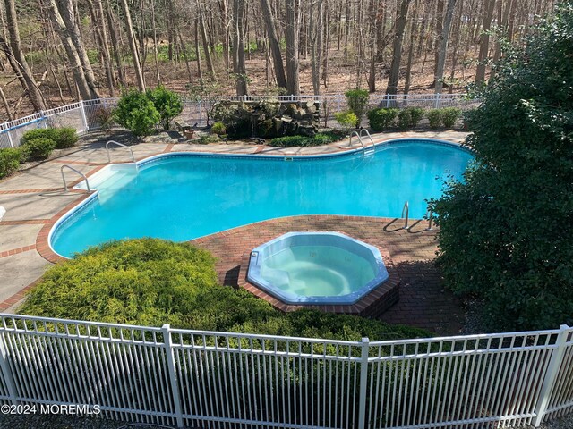 view of pool with a patio area and an in ground hot tub