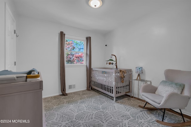 bedroom with light carpet and a nursery area