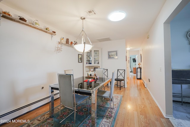 dining area featuring a baseboard radiator and light hardwood / wood-style floors