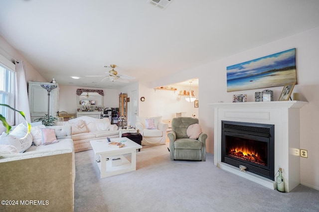 living room featuring light carpet and ceiling fan with notable chandelier