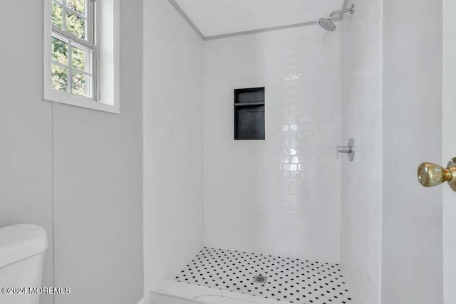 bathroom featuring a tile shower and toilet