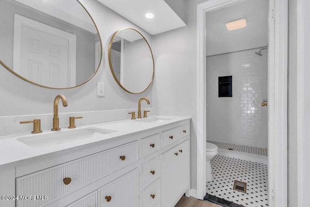 bathroom with a tile shower, vanity, and toilet