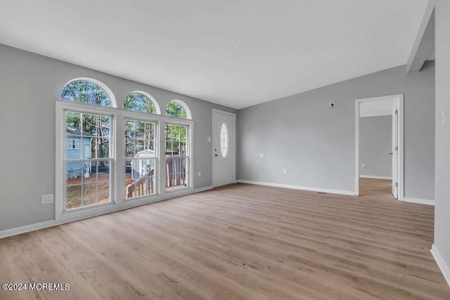 unfurnished living room featuring vaulted ceiling and light wood-type flooring