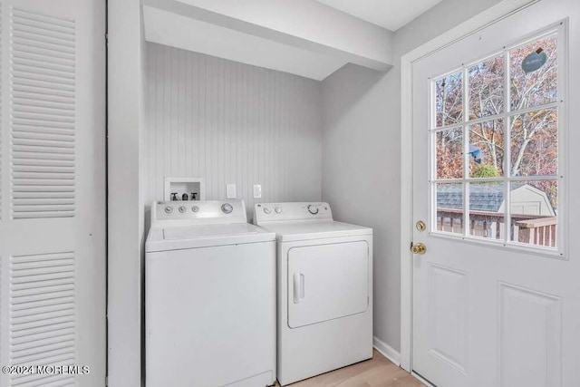 clothes washing area featuring washing machine and clothes dryer and light wood-type flooring