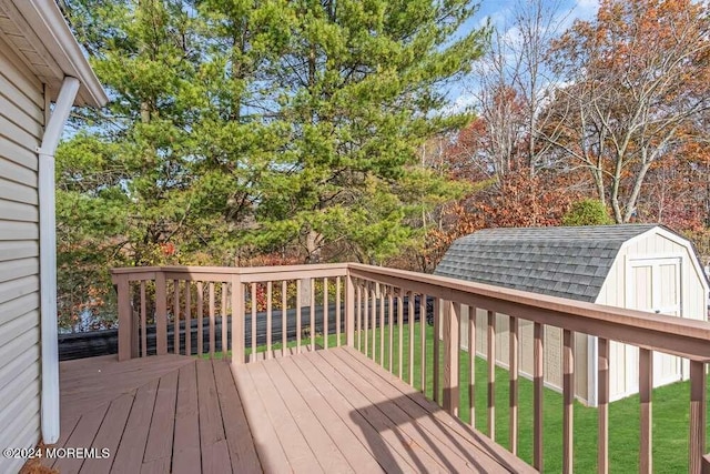 wooden terrace featuring a storage shed and a lawn