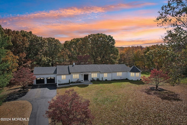 ranch-style home featuring a lawn and a garage