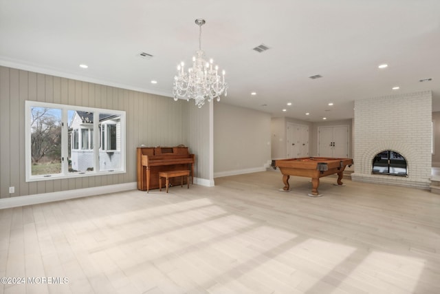 rec room featuring light wood-type flooring, ornamental molding, pool table, and a brick fireplace