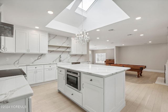 kitchen featuring pendant lighting, white cabinets, a skylight, pool table, and a kitchen island