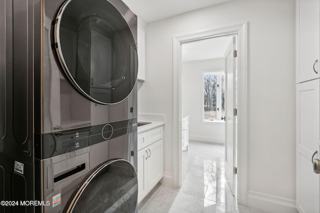 laundry room featuring cabinets and stacked washing maching and dryer