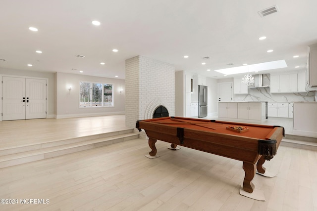 playroom with a fireplace, light hardwood / wood-style floors, and pool table