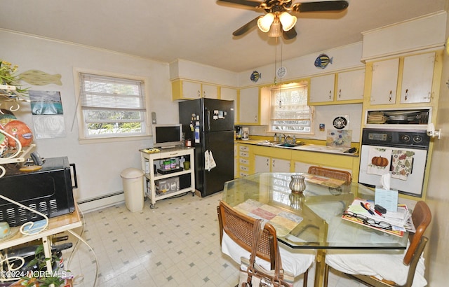 kitchen featuring oven, black fridge, sink, ornamental molding, and a baseboard radiator