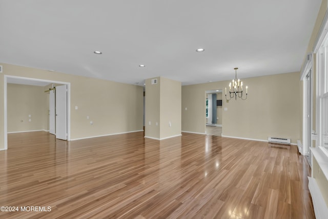 unfurnished room with a notable chandelier, baseboard heating, and light hardwood / wood-style flooring