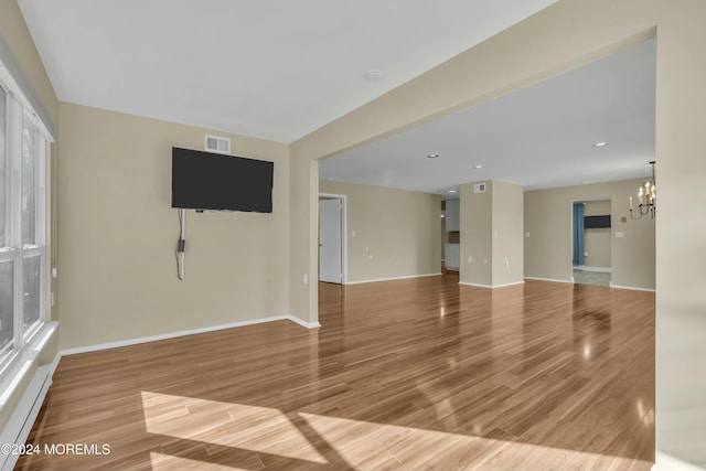 empty room featuring a notable chandelier and hardwood / wood-style floors