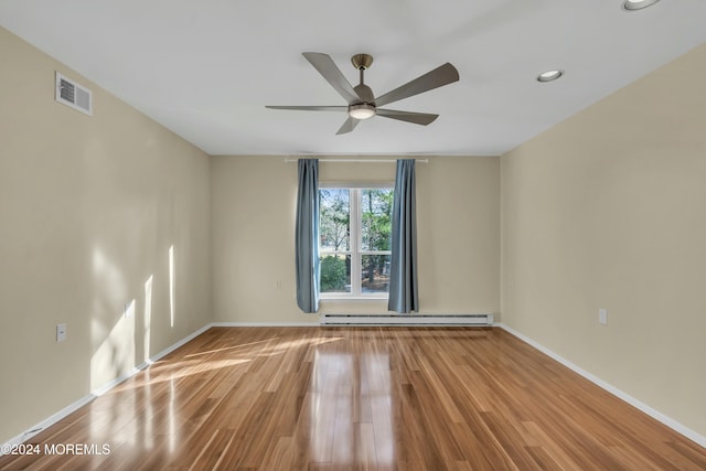 empty room featuring ceiling fan, light wood-type flooring, and baseboard heating