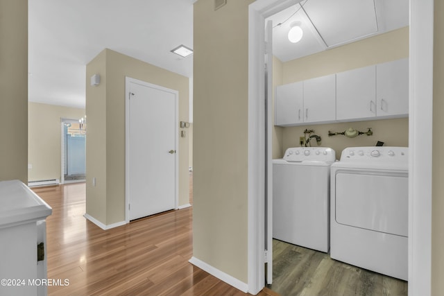 washroom featuring cabinets, hardwood / wood-style flooring, and washing machine and clothes dryer