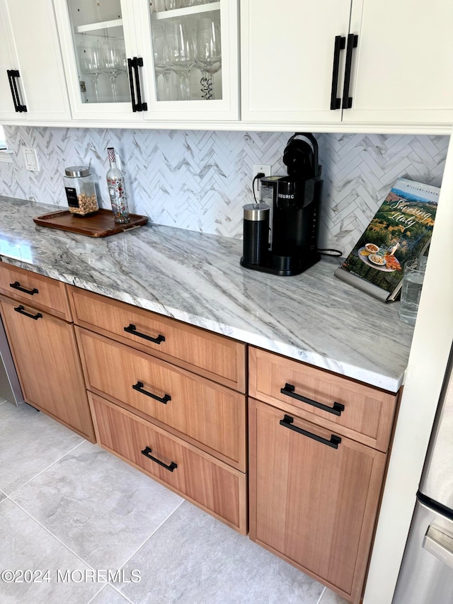 kitchen with decorative backsplash, white cabinetry, light tile patterned flooring, and light stone countertops