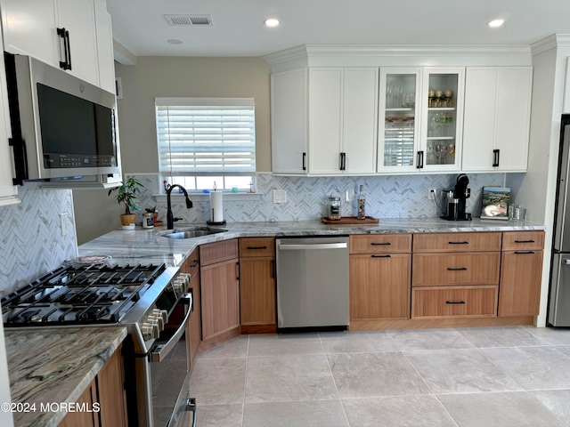 kitchen featuring light stone countertops, sink, backsplash, white cabinets, and appliances with stainless steel finishes