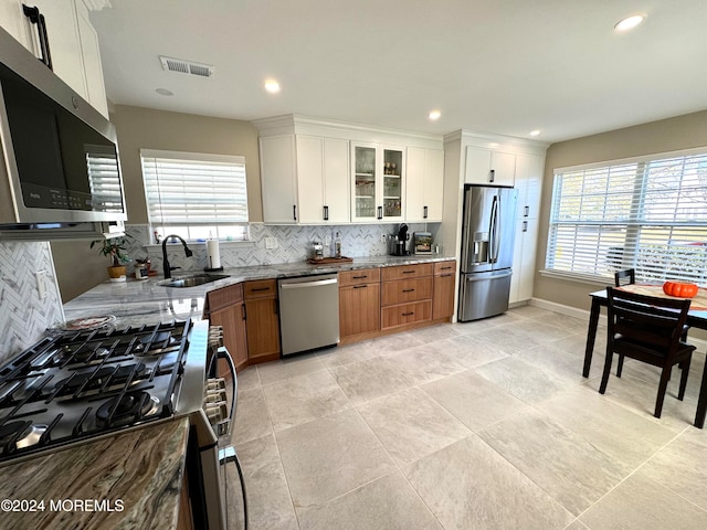 kitchen featuring white cabinets, decorative backsplash, stainless steel appliances, and a wealth of natural light