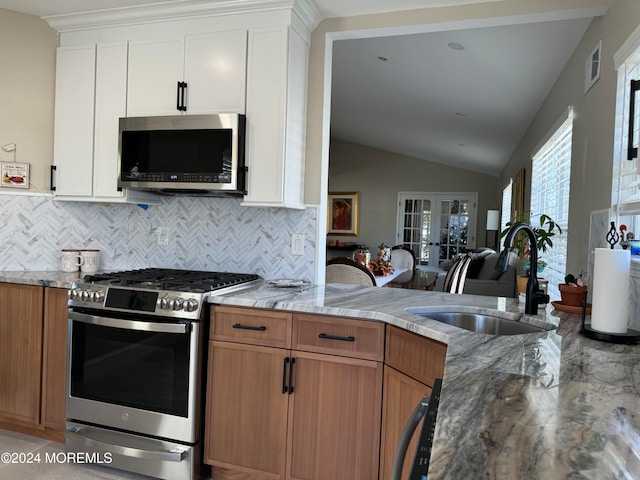 kitchen featuring white cabinets, sink, decorative backsplash, appliances with stainless steel finishes, and light stone counters