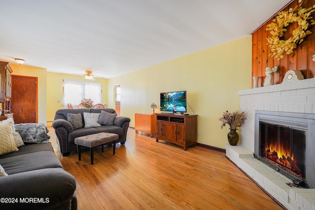 living room with a fireplace, ceiling fan, and light hardwood / wood-style flooring