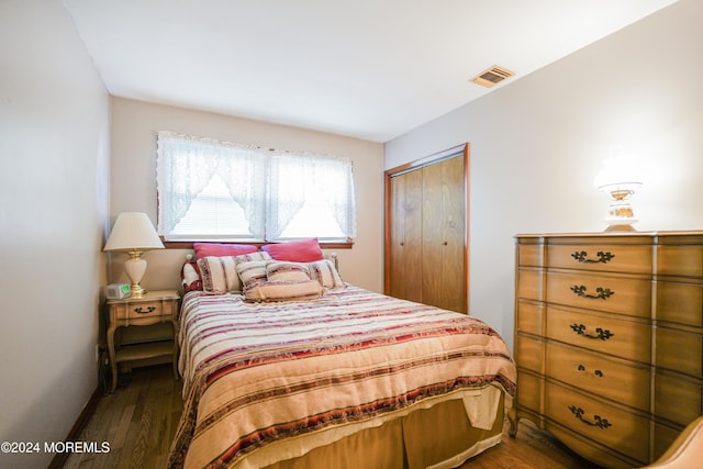 bedroom with dark hardwood / wood-style floors and a closet