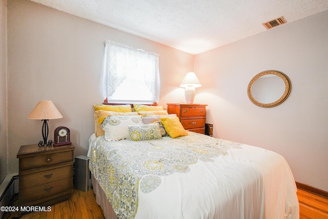 bedroom featuring hardwood / wood-style flooring and a textured ceiling