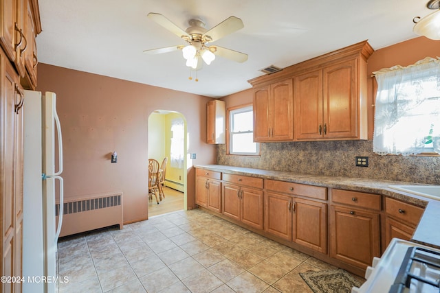 kitchen featuring backsplash, ceiling fan, light tile patterned floors, radiator heating unit, and white fridge