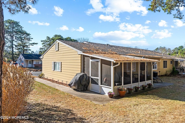 rear view of house featuring a lawn and a sunroom