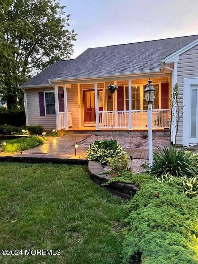 rear view of house with covered porch and a lawn