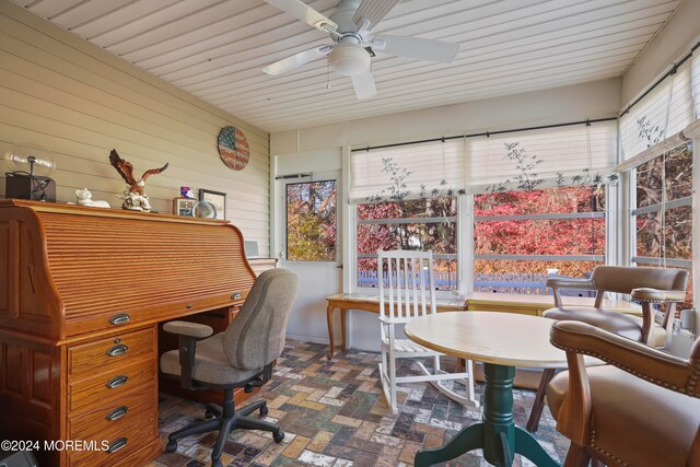 home office featuring ceiling fan and wood walls