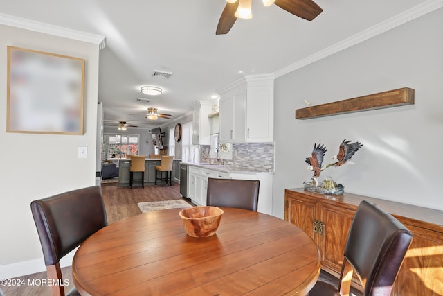 dining space featuring crown molding, dark wood-type flooring, and sink