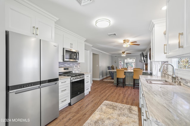 kitchen featuring sink, light wood-type flooring, light stone counters, white cabinetry, and stainless steel appliances