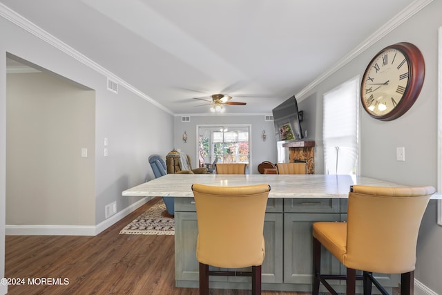 dining room with dark hardwood / wood-style flooring, a stone fireplace, ceiling fan, and ornamental molding