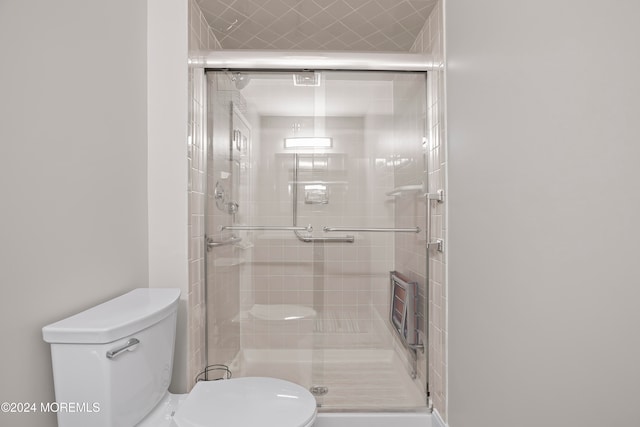 bathroom featuring toilet and a shower with shower door