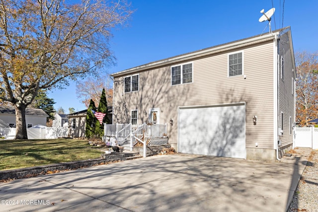 rear view of property with a yard, a deck, and a garage