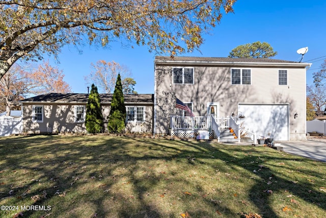 rear view of house featuring a garage, a yard, and a wooden deck