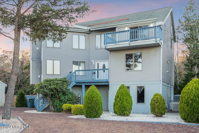 back house at dusk featuring a balcony